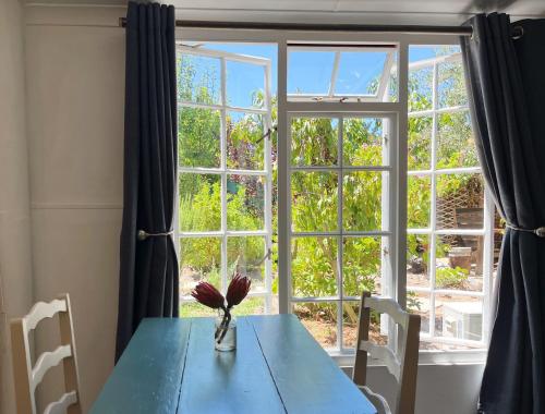 une table bleue avec un vase devant une fenêtre dans l'établissement Equleni Guest Farm, à Sedgefield