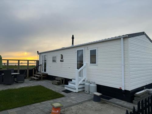 a white tiny house on a patio with the ocean at Prachtig chalet de ZEE STER in Westerland
