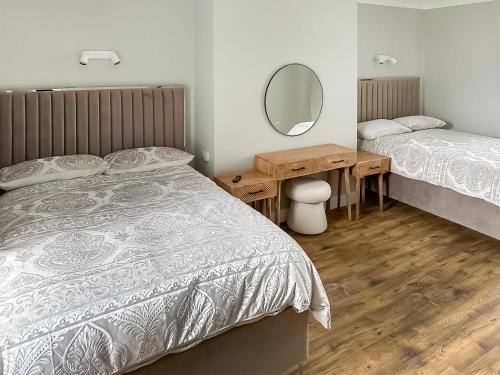 a bedroom with two beds and a desk with a mirror at Lilydale Retreat in Lanchester