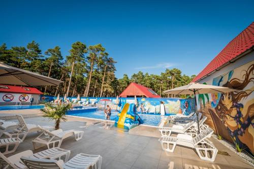a swimming pool with white chairs and a water park at AMBRE Domki letniskowe in Łeba