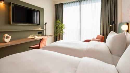 ein Hotelzimmer mit einem Bett und einem TV in der Unterkunft voco Brussels City North, an IHG Hotel in Vilvoorde