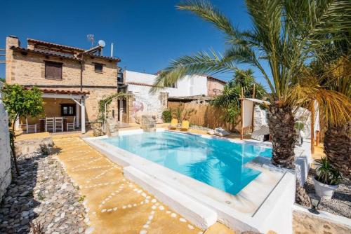 a swimming pool with a palm tree next to a house at Villa Hidden Gem Crete in Pangalochori