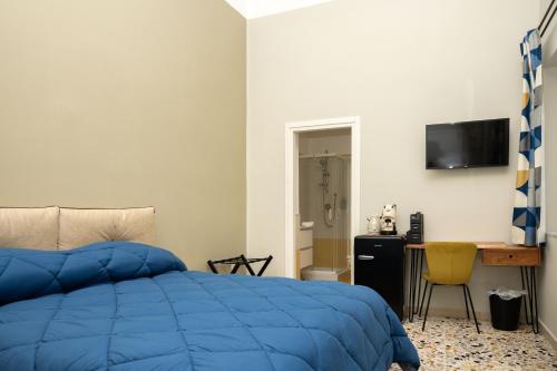 1 dormitorio con cama azul y escritorio en Pignuol Rooms - nel cuore di Marigliano, en Marigliano