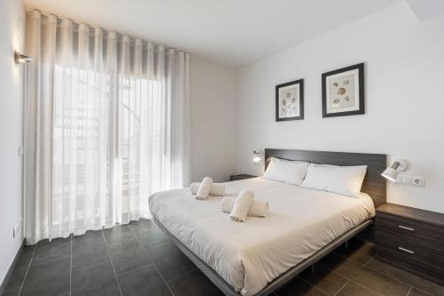 a white bedroom with a large bed with white pillows at Apartamento ático primera línea Playa Canyelles in Roses