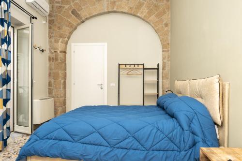 Una gran cama azul en una habitación con una pared de ladrillo en Pignuol Rooms - nel cuore di Marigliano, en Marigliano