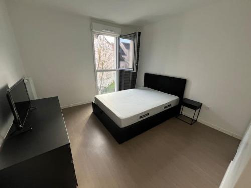 ein kleines Schlafzimmer mit einem Bett und einem Fenster in der Unterkunft Appartement T2 2e etage parking gratuit sur place in Cergy