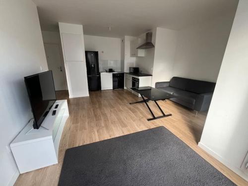 ein Wohnzimmer mit einem Sofa und einem TV in der Unterkunft Appartement T2 2e etage parking gratuit sur place in Cergy