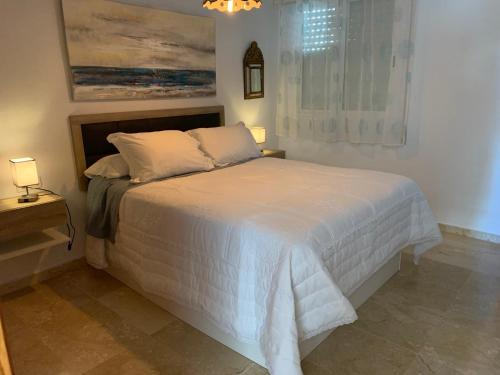Apartamento Cielo Azul في روكويتاس دي مار: غرفة نوم بسرير ابيض مع وسادتين