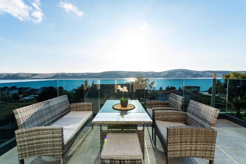 een patio met rieten stoelen en een tafel op een balkon bij La Vie luxury apartments with a pool in Stara Novalja