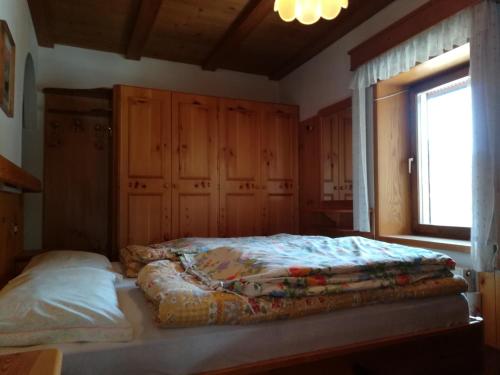a bedroom with a bed with wooden cabinets and a window at Appartamento La Mirandola Rosso in Livinallongo del Col di Lana