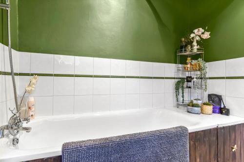 a bathroom with a bath tub with a green wall at Victorian cottage in Brixton! in London