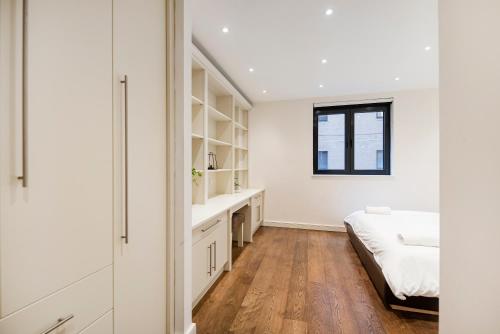 a white bedroom with a bed and a window at Central 2 Bed Maissonette in London