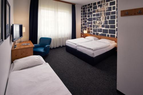 a hotel room with two beds and a chair at Hotel Hamburg-Wittenburg van der Valk in Wittenburg