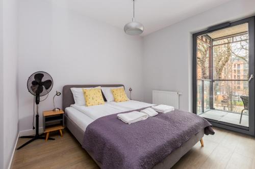 een slaapkamer met een bed met een paarse deken en een raam bij Złota Łąka Cosy Apartment in Gdańsk
