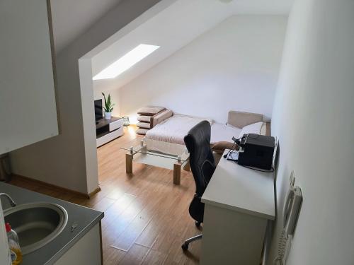 Habitación con cama y escritorio con silla. en ATTICA APARTMENTS en Bijelo Polje