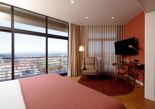 a hotel room with a bed and a desk and a window at Montebelo Viseu Congress Hotel & Spa in Viseu