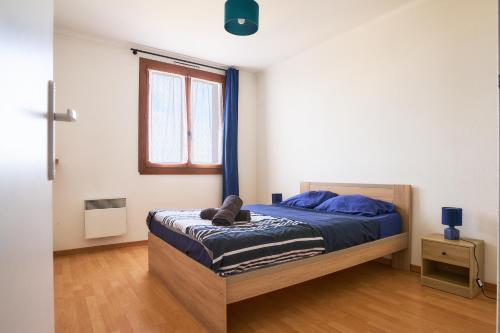 une chambre avec un lit avec des draps bleus et une fenêtre dans l'établissement Appartement Cosy proche Gare TGV et Centre ville., à Avignon