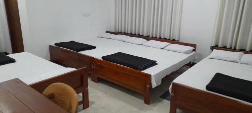 迪亞塔拉瓦的住宿－Sahasna Guest House，带三张床、一张桌子和椅子的房间