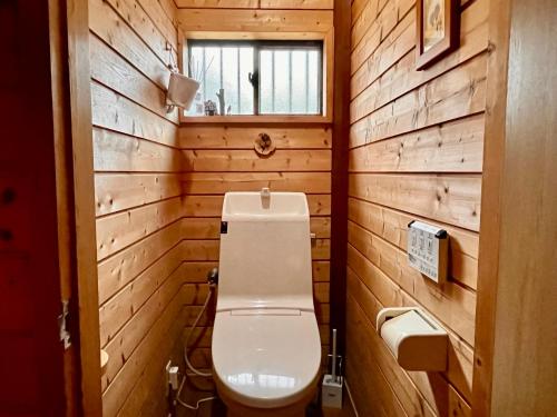 a bathroom with a toilet in a wooden wall at beau lac biwako in Takashima