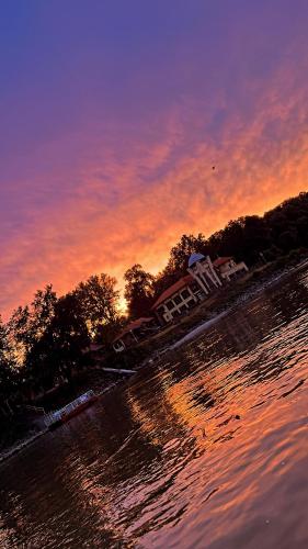 a sunset on the shore of a body of water at SZIGET HOTEL VERÁNKA in Érsekcsanád