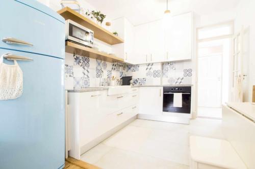uma cozinha com armários brancos e um frigorífico azul em Moeda '60 - Downtown Apartment em Coimbra