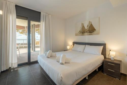 a bedroom with a large white bed and a balcony at Apartamento con gran terraza delante del mar in Roses