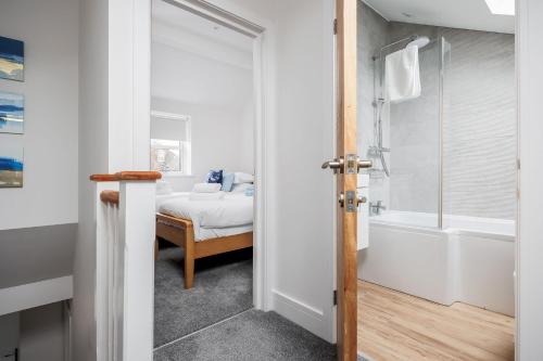 uma casa de banho com uma cama, um chuveiro e uma banheira em Charlotte Cottage em Poole