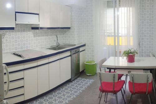 eine Küche mit einem Waschbecken und einem Tisch mit roten Stühlen in der Unterkunft Piso en Ourense- Sempre Maruxiña in Ourense