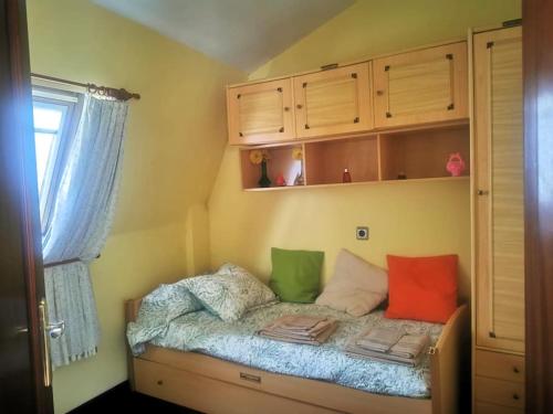 a small bed with colorful pillows in a room at INcostadamorte Apartamento Estrela 14 in Cee