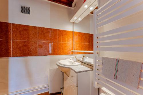 baño con lavabo blanco y paredes de azulejos de color naranja. en La halte de Compostelle, en Belin-Beliet