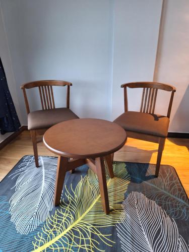 - deux chaises et une table sur un tapis dans une chambre dans l'établissement Bunny Homestay 405MB @ ROXY Apartment Kuching, à Kuching