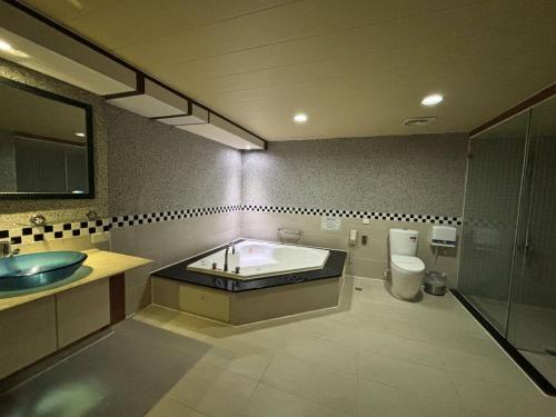 a bathroom with a tub and a toilet and a sink at Hua Xiang Motel - Da Chang in Kaohsiung