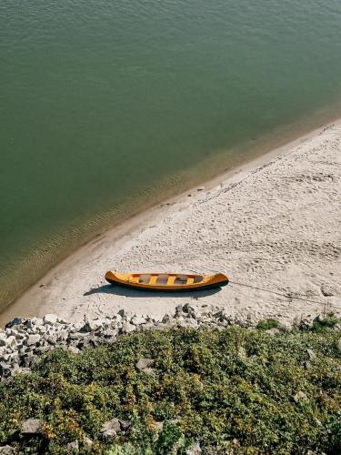 an orange kayak sitting on the beach next to the water at SZIGET HOTEL VERÁNKA in Érsekcsanád