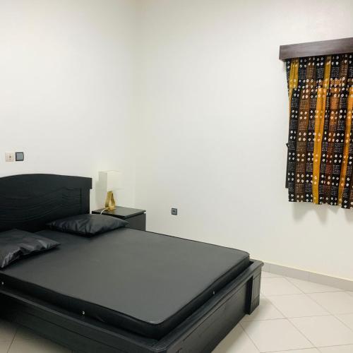 a bedroom with a black bed and a window at Charly Arconville i in Abomey-Calavi