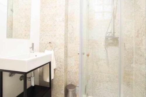 Un baño blanco con lavabo y ducha. en Moeda ‘60 - Second Floor, en Coímbra