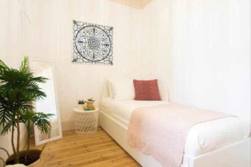 Un dormitorio con una cama blanca y una planta. en Moeda ‘60 - Second Floor, en Coímbra