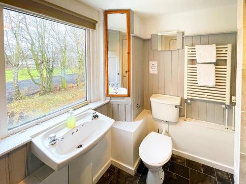 een badkamer met een wastafel, een toilet en een raam bij Harvieston Hall in Gorebridge