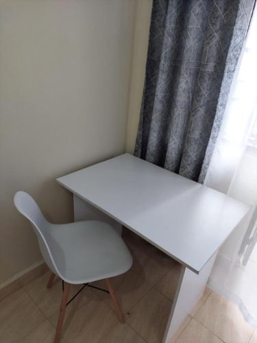 białe biurko i krzesło obok okna w obiekcie Kim's BNBs w mieście Meru