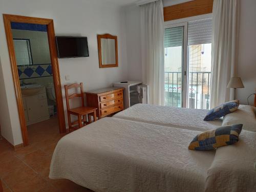 a hotel room with two beds and a window at Hostal Ana - Adults Recommended in Nerja