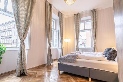 a bedroom with a bed and two large windows at Metropolitan Charm: Stylish 2+1 Apt@ Vienna's Core in Vienna