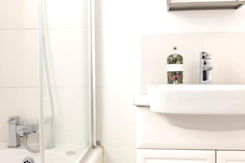 y baño blanco con lavabo y ducha. en Apartment with canal view in Broadway Market en Londres