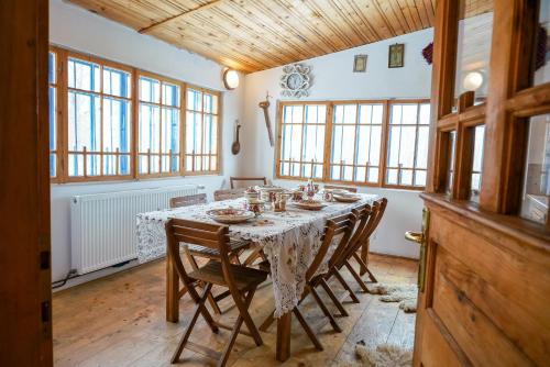 ein Esszimmer mit einem Tisch mit Stühlen und Fenstern in der Unterkunft Casa Plaiul Cailor: Rustic Mountain Hideaway in Proviţa de Sus