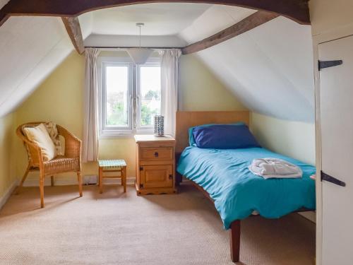 a bedroom with a bed and a chair and a window at Findley Cottage 