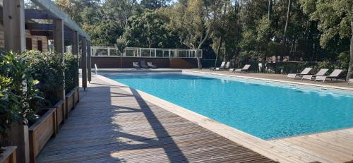 una piscina con sillas y una terraza de madera en Chalet la lande en Ondres
