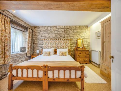 a bedroom with a bed and a stone wall at Capp Mill in Painswick