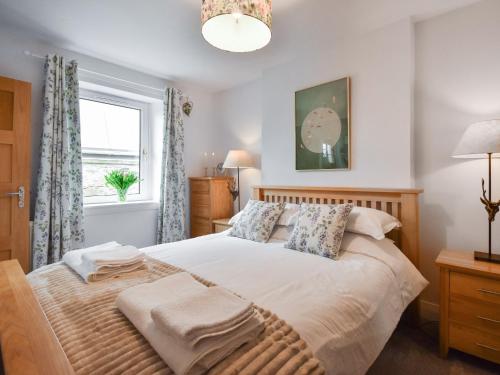 1 dormitorio con 1 cama grande y ventana en Southbank Cottage, en Errol