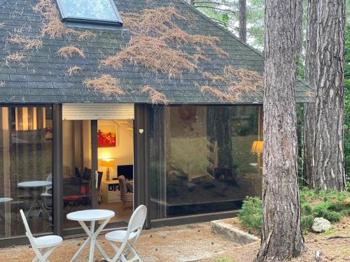 una casa de cristal en el bosque con mesa y sillas en La Forestière - Face au 10, en Neufchâtel-Hardelot
