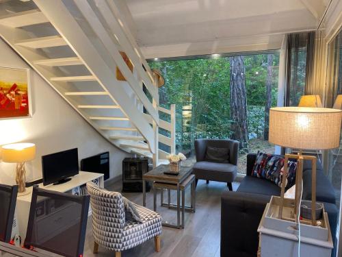 uma sala de estar com uma escada e um sofá e cadeiras em La Forestière - Face au 10 em Neufchâtel-Hardelot