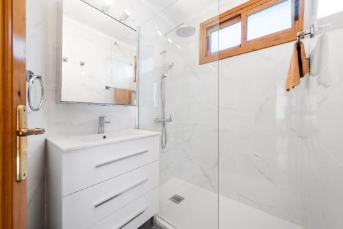 uma casa de banho branca com um chuveiro e um lavatório. em Apartamento Lortal em Alcudia