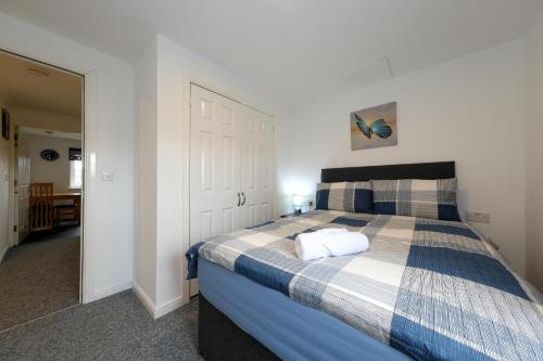 a bedroom with a bed with a blue and white blanket at Pure Apartments 2 Bed Duloch - Dunfermline in Fife